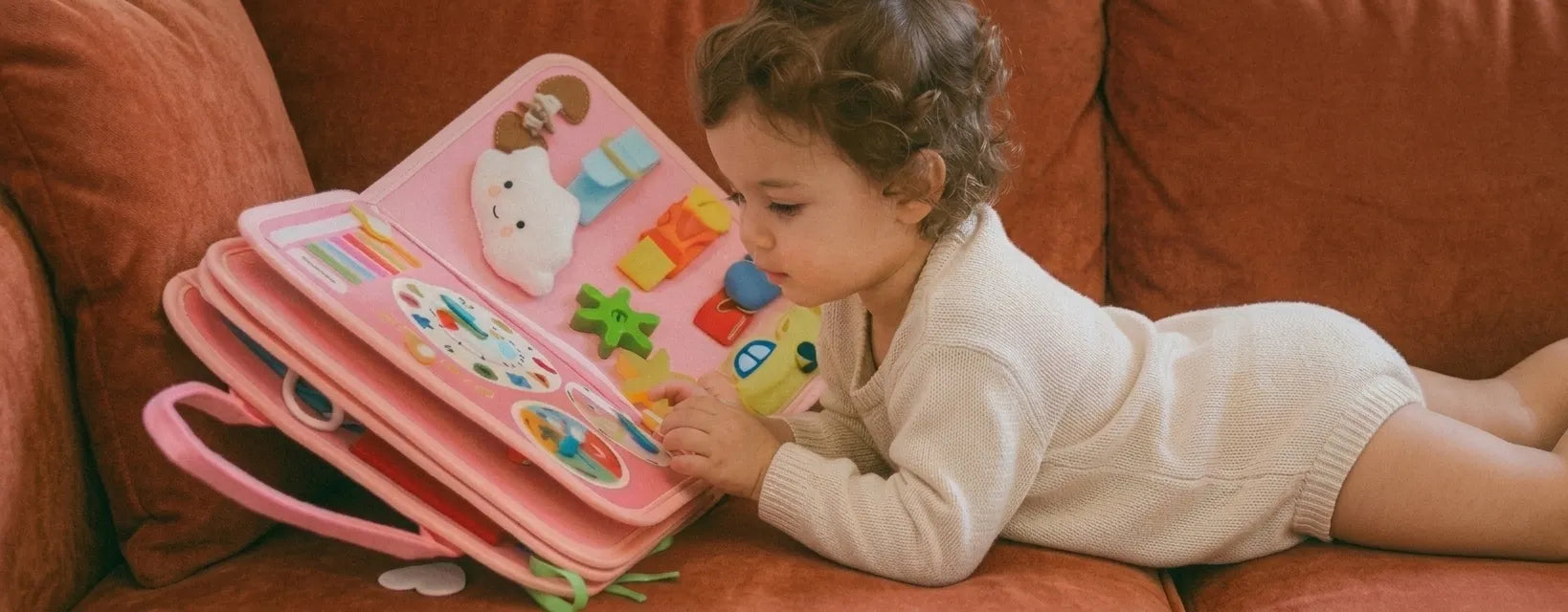 Bambina sdraiata sul divano gioca con la valigetta Manine rosa