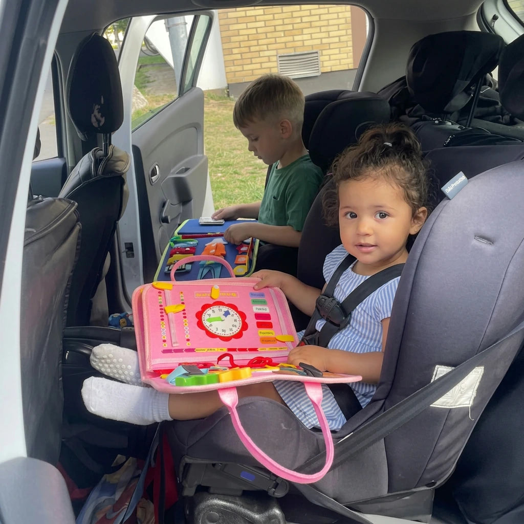 Bambina nel seggiolino auto gioca con la valigetta Manine rosa durante il viaggio